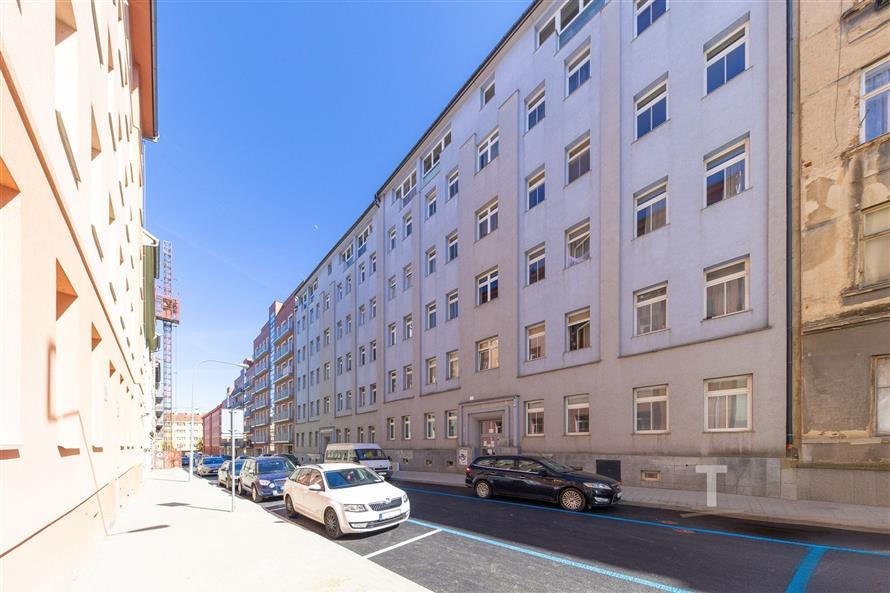 Pohled na zrekonstruovaný městský dům s velkými okny a světlou omítkou, nacházející se v centru města s dobrým dopravním spojením.
