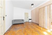 Světlý obývací pokoj s parketovou podlahou, vestavěnými skříněmi a světlým nádechem nabízí moderní a prostorný interiér.