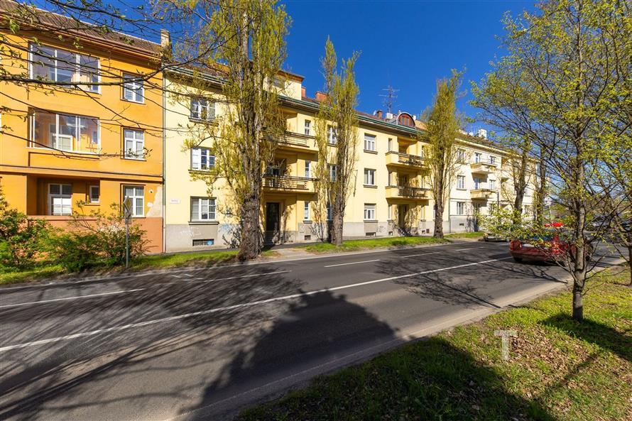 Exteriér bytového domu s historickými prvky, nová fasáda, klidná rezidenční čtvrť, udržovaná zeleň, výborná dostupnost do centra města.