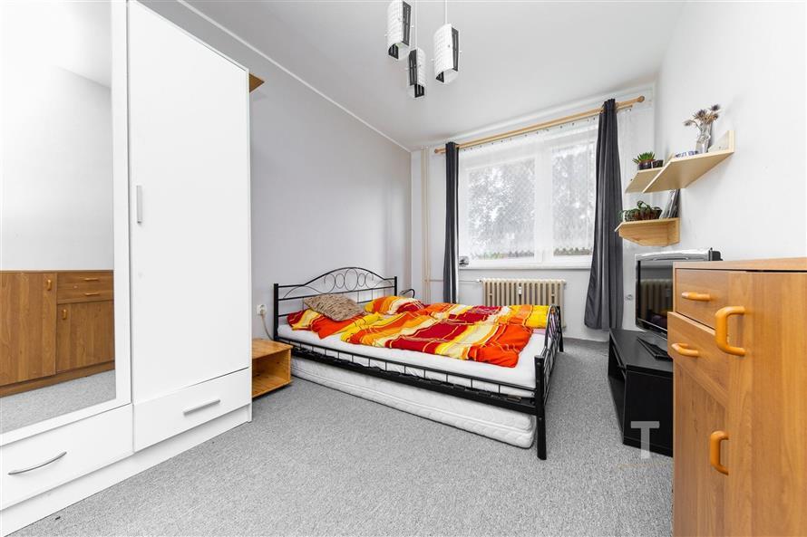 Ložnice s koberci, vestavěnou skříní a velkými okny zajišťujícími dostatek světla, moderní a útulné místo k relaxaci.