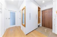 Vstupní hala s dřevěnou podlahou, vestavěnými skříněmi a moderními dveřmi, nabízí světlé a funkční úložné prostory.