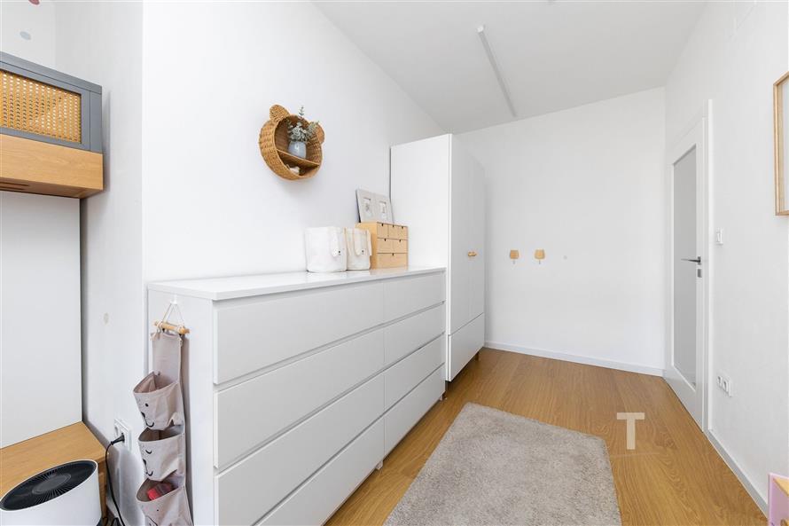 Dětský pokoj s parketovou podlahou, moderní světlé stěny, vestavěné skříně a dekorativní prvky.