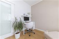 Moderní pracovní kout s parketovou podlahou, světlé stěny, vestavěné úložné prostory, minimalistický designový kancelářský nábytek.