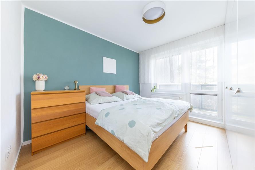 Prostorná ložnice s moderním designem, dřevěná podlaha, velká okna pro přirozené světlo, vestavěné skříně pro úložný prostor.