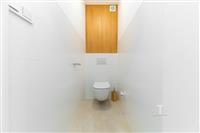 Úzká moderní toaleta s bílými dlaždicemi, dřevěný panel, minimalistický design, světlý interiér