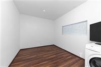 Prázdný pokoj s parketovou podlahou, bílými stěnami a moderním osvětlením; ideální pro rekonstruovaný interiér.