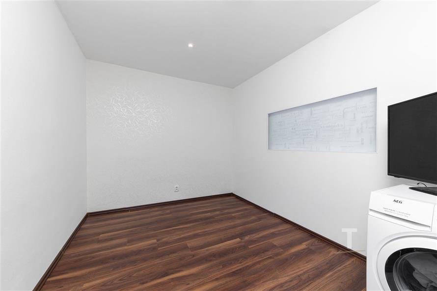 Prázdný pokoj s parketovou podlahou, bílými stěnami a moderním osvětlením; ideální pro rekonstruovaný interiér.