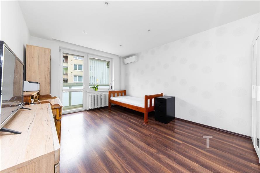 Světlý obývací pokoj s parketovou podlahou, velká okna a moderní výzdoba.