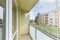 Zasklený balkon s dlažbou, moderní úprava, výhled na okolní zástavbu a zeleň, ideální pro relaxaci.