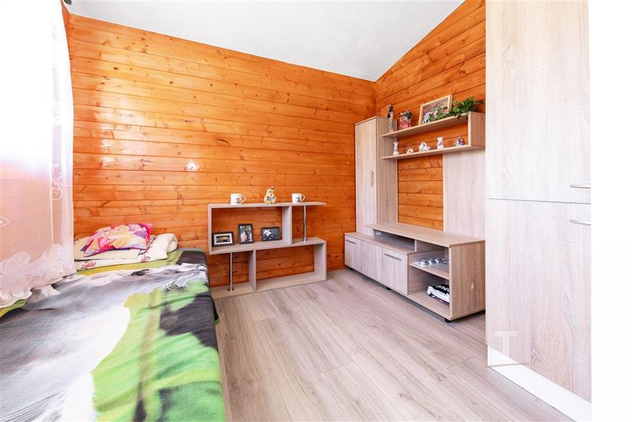 Světlý dětský pokoj s dřevěným obložením, parketovou podlahou a vestavěnými skříněmi, vytvářející útulnou atmosféru.