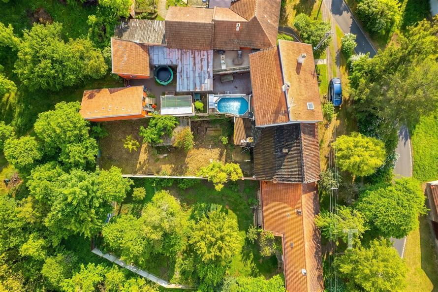 Letecký pohled na venkovský dům s červenou střešní krytinou, bazénem a zahradou. Poklidná lokalita obklopená zelení nabízí soukromí a prostor.