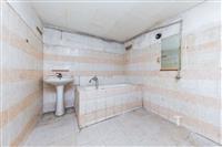 Koupelna s dlažbou, vanou a umyvadlem vyžaduje rekonstrukci, základní zařízení a starší styl nabízí potenciál pro modernizaci.