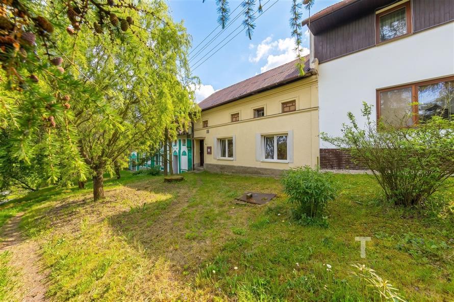 Exteriér rodinného domu s velkou zahradou, udržovaný trávník, vzrostlé stromy, renovovaná fasáda, klidná lokalita.