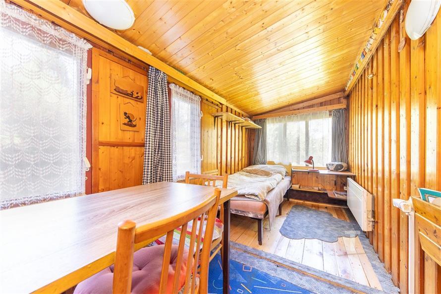 Dřevěná ložnice s parketovou podlahou, velkými okny a dřevěným stropem poskytuje útulný a tradiční styl bydlení.