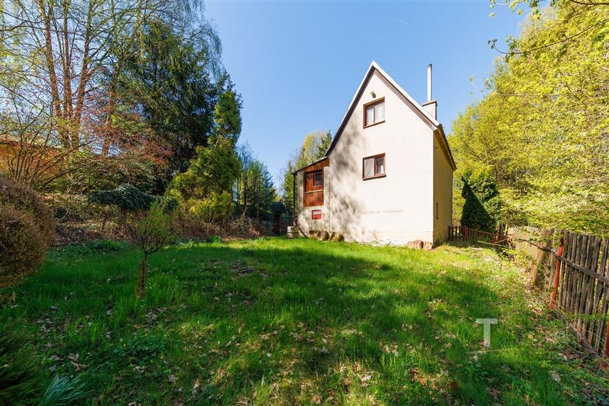 Zahrada u rodinného domu s trávníkem, lesní okolí, dřevěný plot, klidná lokalita.