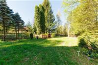 Prostorná zahrada s travnatým porostem, vzrostlé stromy poskytující stín a klid, ideální pro relaxaci a venkovní aktivity v přírodě.