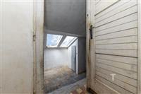 Malý podkrovní prostor s šikmými okny a dlažbou. Interiér potřebuje renovaci, má potenciál pro světlou a vzdušnou místnost.