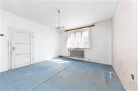 Světlý pokoj s velkým oknem, starší koberce a bílá omítka, možnost rekonstrukce, klidné prostředí.