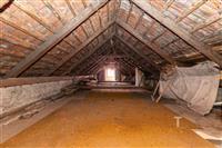 Půdní prostor s dřevěným krovem a cihlovou střechou, ideální pro rekonstrukci, nabízí prostorné možnosti pro využití dle vlastní potřeby.