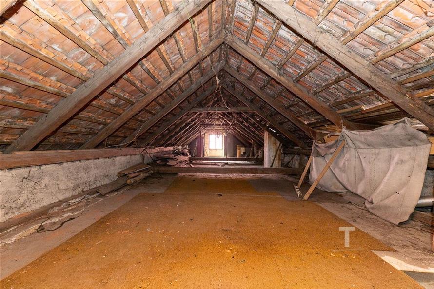 Půdní prostor s dřevěným krovem a cihlovou střechou, ideální pro rekonstrukci, nabízí prostorné možnosti pro využití dle vlastní potřeby.