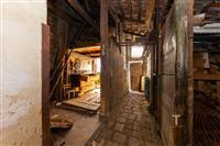 Starý přístavek se dřevěnými trámy, povrch z cihel a prken, potřebuje rekonstrukci.