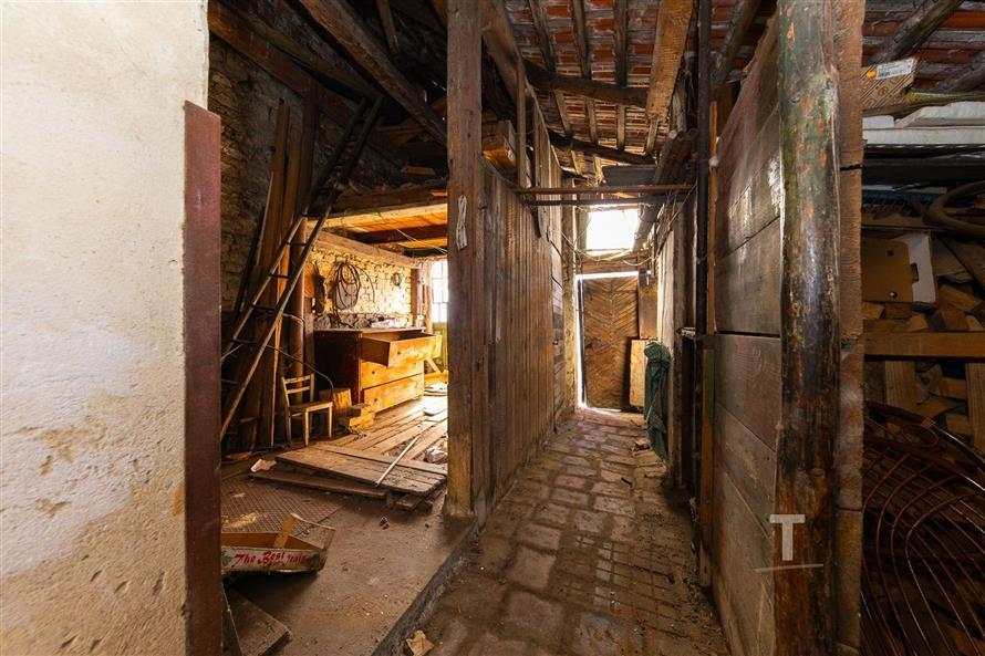 Starý přístavek se dřevěnými trámy, povrch z cihel a prken, potřebuje rekonstrukci.