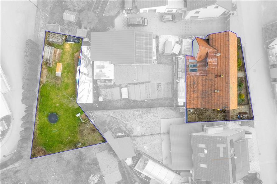 Dům s červenou střechou a rozlehlá zahrada. Venkovní prostor zahrnuje trávník a úložný prostor. Nemovitost se nachází v rezidenční oblasti.