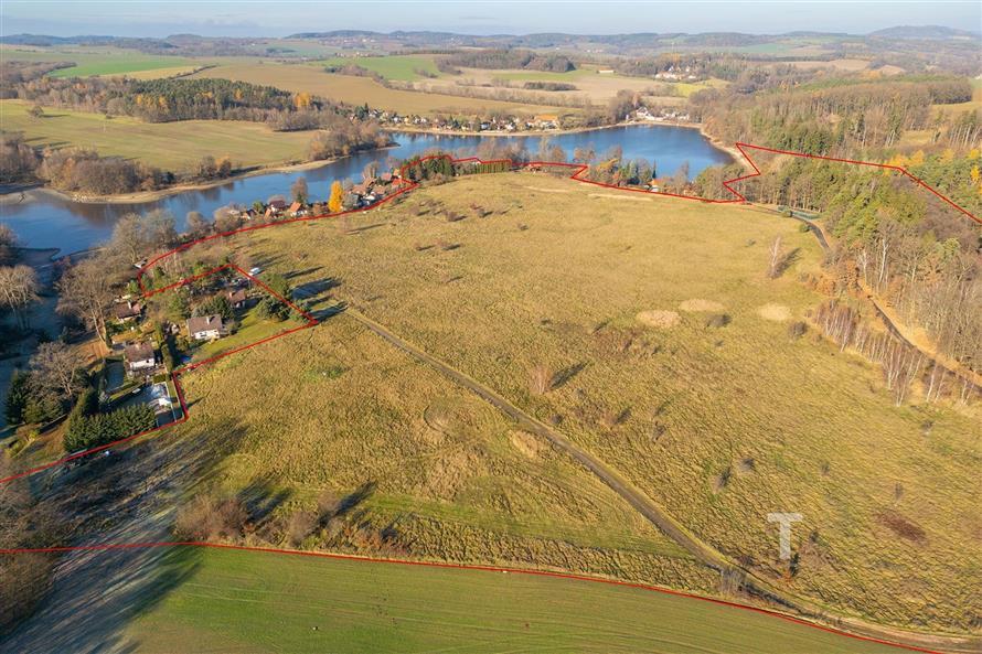 Rozlehlý pozemek s malebným výhledem na jezero, obklopený přírodou, ideální pro klidný život nebo rekreační využití, v atraktivní lokalitě.