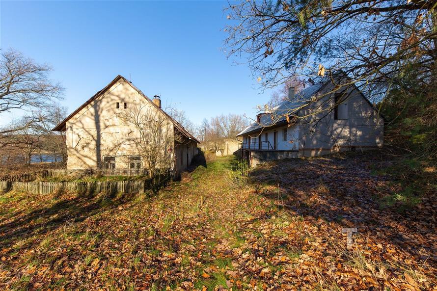 Dvě vesnické chalupy s dřevěnými ploty na prostorném pozemku, obklopené přírodou a stromy, ideální pro rekonstrukci a klidné bydlení.