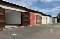 Garážová jednotka s nově natřenými dveřmi, betonovou podlahou a bezpečnostním oplocením udržovaná v dobrém stavu vhodná pro parkování.