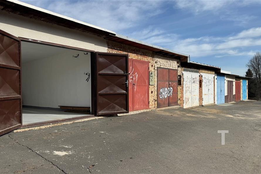 Garážová jednotka s nově natřenými dveřmi, betonovou podlahou a bezpečnostním oplocením udržovaná v dobrém stavu vhodná pro parkování.