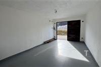 Prostorná garáž s betonovou podlahou, bílými stěnami a masivními kovovými vraty, ideální pro bezpečné parkování vozidla.