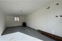 Prázdná garáž s betonovou podlahou, bílými stěnami a malým čtvercovým oknem, připravená k přizpůsobení.