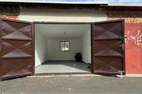 Prázdná garáž s betonovou podlahou a kovovými vraty, ideální pro skladování.