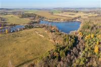 Pozemek u jezera obklopený přírodou s výhledem na lesy a louky, ideální pro rekreaci nebo výstavbu rekreační chaty.
