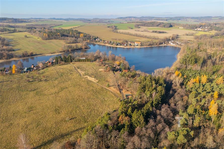 Pozemek u jezera obklopený přírodou s výhledem na lesy a louky, ideální pro rekreaci nebo výstavbu rekreační chaty.
