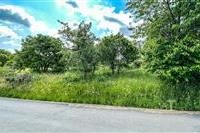 Stavební pozemek s krásným výhledem, obklopený zelení, nabízí klidné prostředí pro výstavbu moderního rodinného domu.