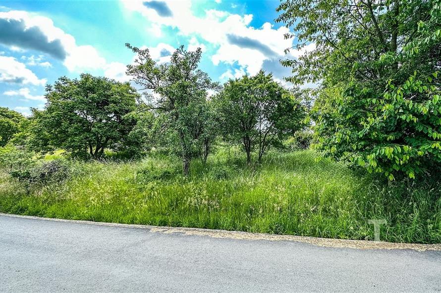 Stavební pozemek s krásným výhledem, obklopený zelení, nabízí klidné prostředí pro výstavbu moderního rodinného domu.