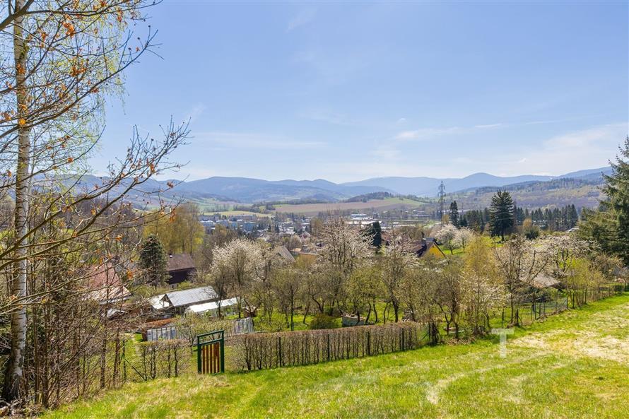 Výhled na malebnou krajinu s rozkvetlými stromy a kopci na obzoru, ideální pro klidné bydlení s přírodními scenériemi.